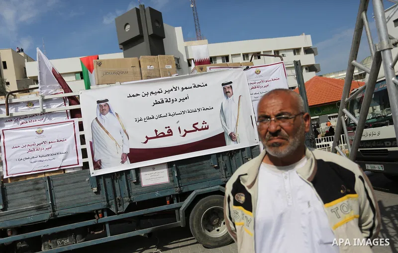 Palestinians walk near the vehicles loaded with humanity aids from Qatar at al-Shifa hospital in Gaza city on February 19, 2018. Photo by Ashraf Amra