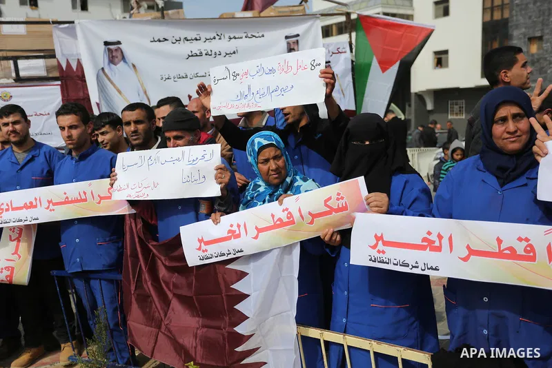 Palestinian cleaners in al-Shifa hospital hold Qatari flags and placards to demand thier salaries during a press conference of Qatar's Ambassador to the Palestinian Authority, Mohammed Al Emadi in Gaza city on February 1...