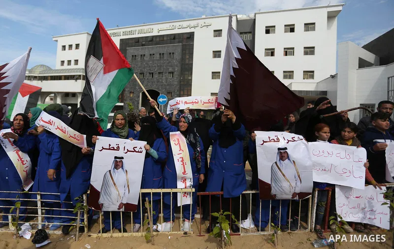 Palestinian cleaners in al-Shifa hospital hold Qatari flags and placards to demand thier salaries during a press conference of Qatar's Ambassador to the Palestinian Authority, Mohammed Al Emadi in Gaza city on February 1...