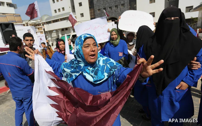 Palestinian cleaners in al-Shifa hospital hold Qatari flags and placards to demand thier salaries during a press conference of Qatar's Ambassador to the Palestinian Authority, Mohammed Al Emadi in Gaza city on February 1...