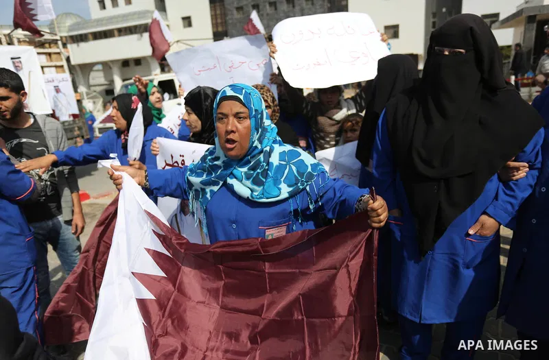 Palestinian cleaners in al-Shifa hospital hold Qatari flags and placards to demand thier salaries during a press conference of Qatar's Ambassador to the Palestinian Authority, Mohammed Al Emadi in Gaza city on February 1...