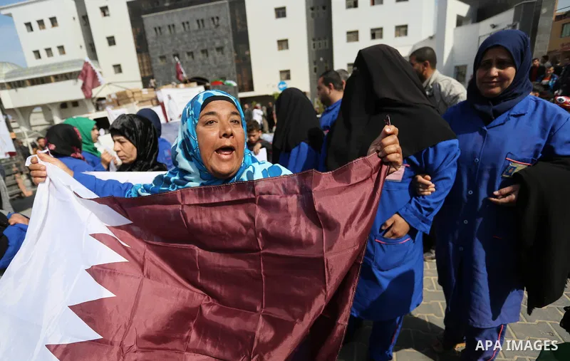 Palestinian cleaners in al-Shifa hospital hold Qatari flags and placards to demand thier salaries during a press conference of Qatar's Ambassador to the Palestinian Authority, Mohammed Al Emadi in Gaza city on February 1...