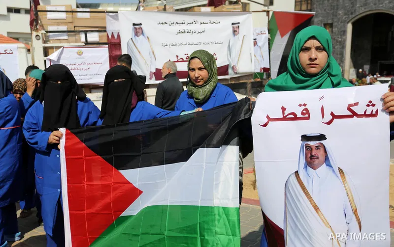 Palestinian cleaners in al-Shifa hospital hold Qatari flags and placards to demand thier salaries during a press conference of Qatar's Ambassador to the Palestinian Authority, Mohammed Al Emadi in Gaza city on February 1...