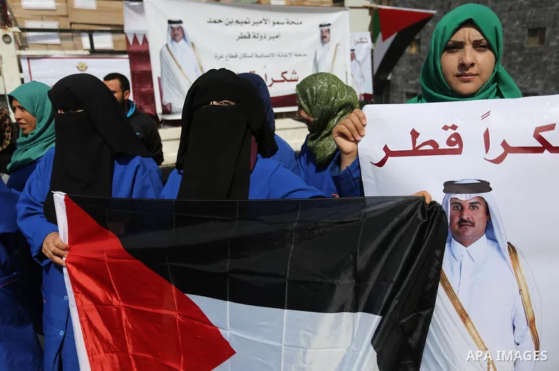 Palestinian cleaners in al-Shifa hospital hold Qatari flags and placards to demand thier salaries during a press conference of Qatar's Ambassador to the Palestinian Authority, Mohammed Al Emadi in Gaza city on February 1...