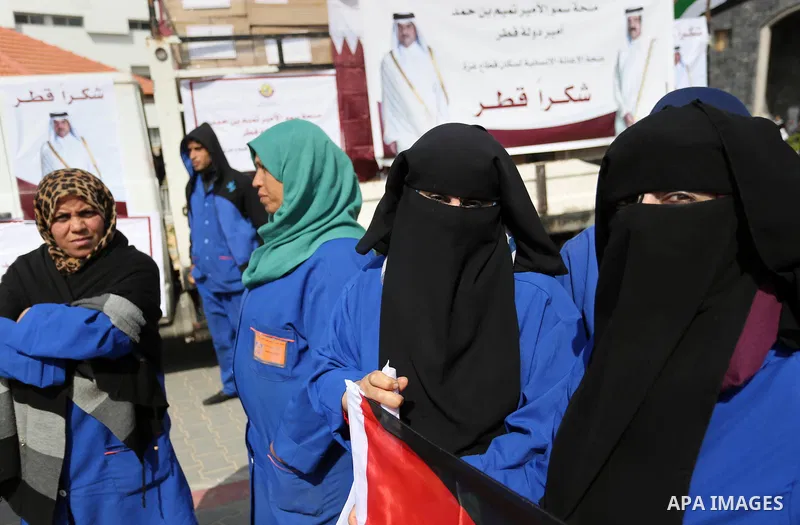 Palestinian cleaners in al-Shifa hospital hold Qatari flags and placards to demand thier salaries during a press conference of Qatar's Ambassador to the Palestinian Authority, Mohammed Al Emadi in Gaza city on February 1...
