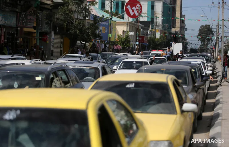 Palestinians stand next to cars in Gaza City on February 20, 2018 during a traffic jam caused by a general strike to protest the humanitarian situation in Gaza. Photo by Ashraf Amra