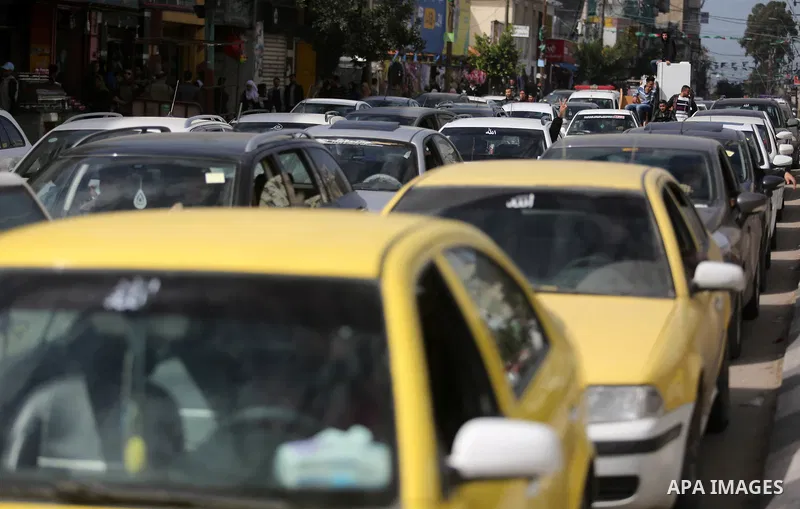 Palestinians stand next to cars in Gaza City on February 20, 2018 during a traffic jam caused by a general strike to protest the humanitarian situation in Gaza. Photo by Ashraf Amra