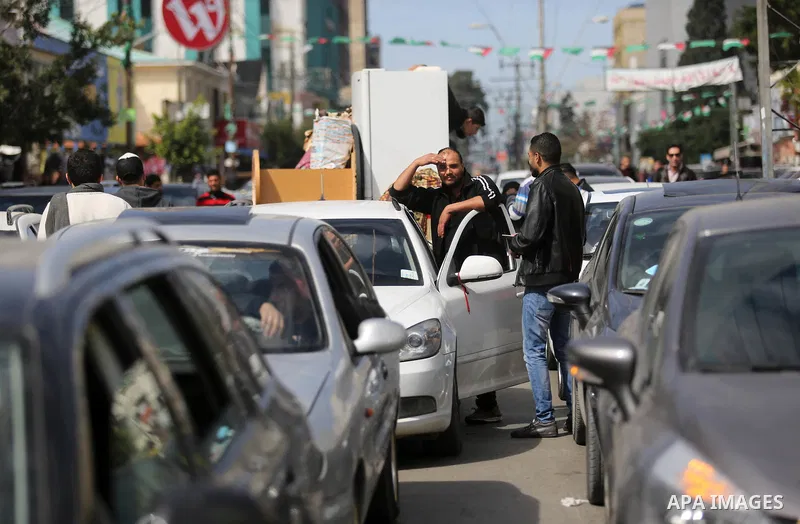Palestinians stand next to cars in Gaza City on February 20, 2018 during a traffic jam caused by a general strike to protest the humanitarian situation in Gaza. Photo by Ashraf Amra