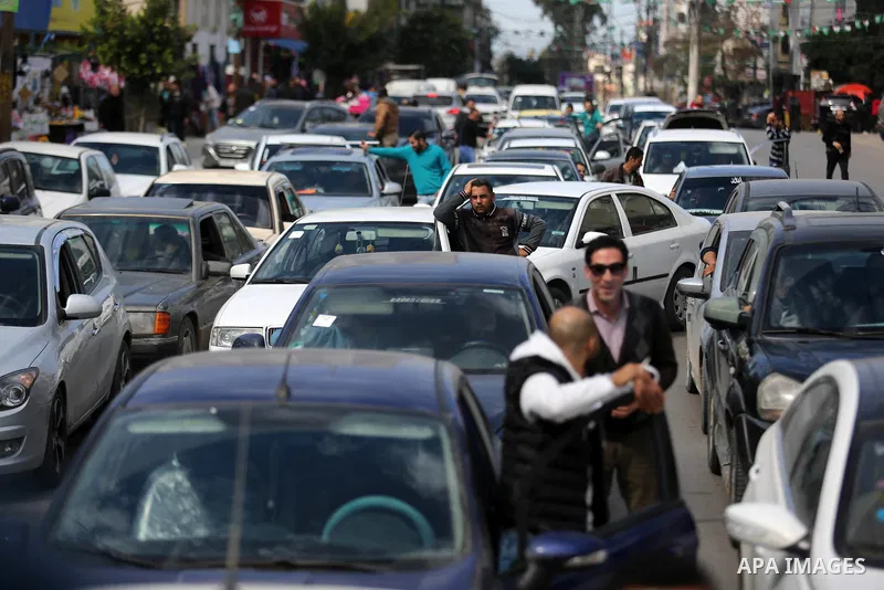 Palestinians stand next to cars in Gaza City on February 20, 2018 during a traffic jam caused by a general strike to protest the humanitarian situation in Gaza. Photo by Ashraf Amra