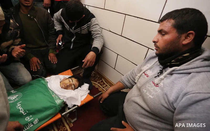 Palestinians gather over the body of Ahmed Ebu Helou, 19, who died of his injuries after Israeli security forces shot him during clashes against US decision to recognize Jerusalem as Israel's capital, during his funeral,...