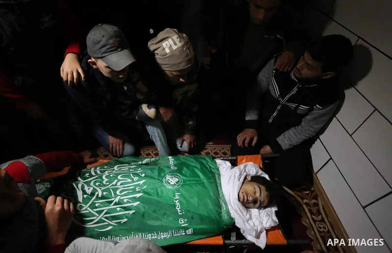 Palestinians gather over the body of Ahmed Ebu Helou, 19, who died of his injuries after Israeli security forces shot him during clashes against US decision to recognize Jerusalem as Israel's capital, during his funeral,...