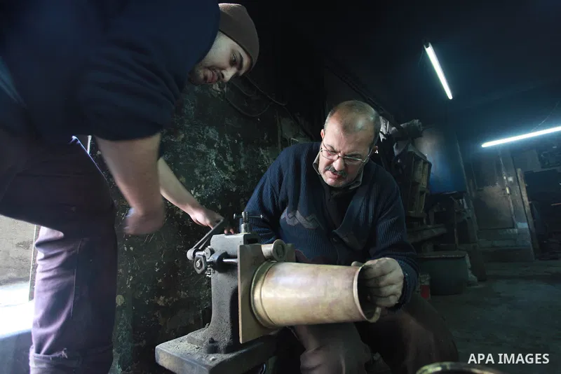 A Palestinian copper, Mohammed Abdo 56, and his son Ahmed work at their workshop, in Gaza city, on February 21, 2018. Abdo inherited copper profession from his father for nearly 40 years. Make replicas Crescent attached...