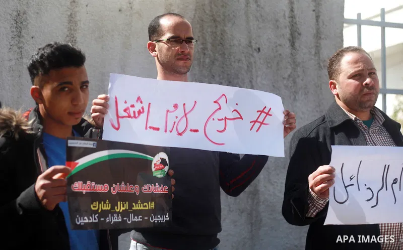 Palestinian graduates hold placards during a protest to demand their rights, outside the Ministry of Labor headquarters in Gaza city on February 25, 2018. Photo by Mahmoud Ajour
