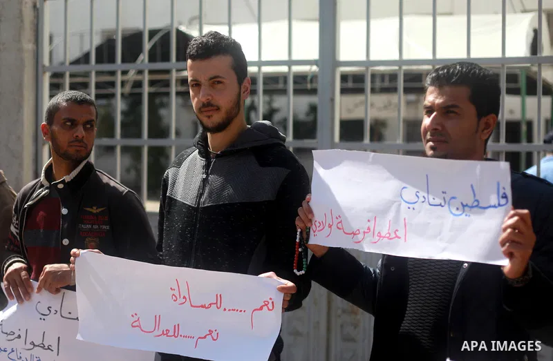Palestinian graduates hold placards during a protest to demand their rights, outside the Ministry of Labor headquarters in Gaza city on February 25, 2018. Photo by Mahmoud Ajour