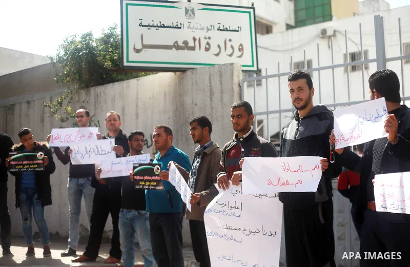 Palestinian graduates hold placards during a protest to demand their rights, outside the Ministry of Labor headquarters in Gaza city on February 25, 2018. Photo by Mahmoud Ajour