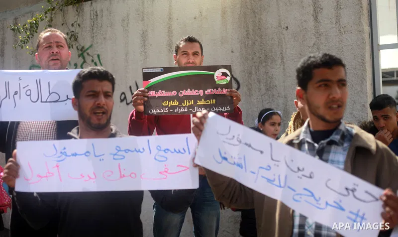 Palestinian graduates hold placards during a protest to demand their rights, outside the Ministry of Labor headquarters in Gaza city on February 25, 2018. Photo by Mahmoud Ajour