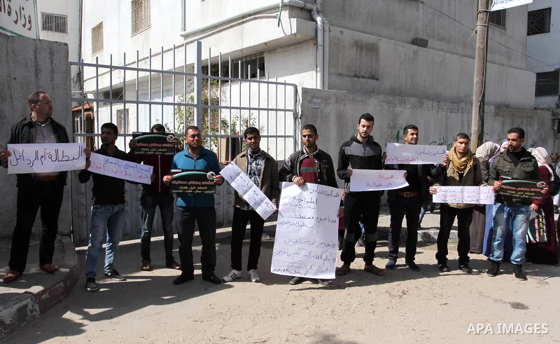 Palestinian graduates hold placards during a protest to demand their rights, outside the Ministry of Labor headquarters in Gaza city on February 25, 2018. Photo by Mahmoud Ajour