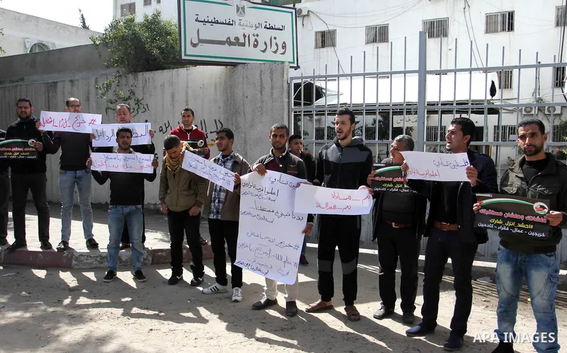 Palestinian graduates hold placards during a protest to demand their rights, outside the Ministry of Labor headquarters in Gaza city on February 25, 2018. Photo by Mahmoud Ajour
