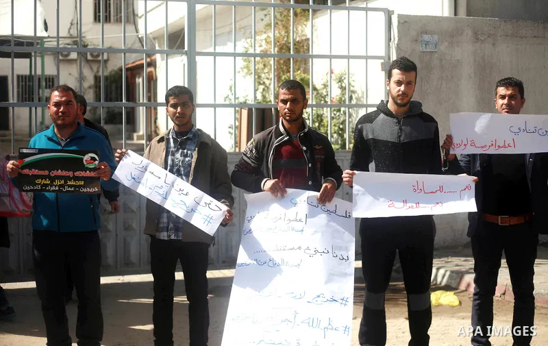 Palestinian graduates hold placards during a protest to demand their rights, outside the Ministry of Labor headquarters in Gaza city on February 25, 2018. Photo by Mahmoud Ajour
