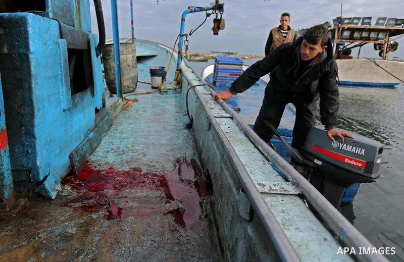 Palestinians inspect a boat at the port in Gaza City on February 26, 2018 in which a fisherman was killed when Israeli forces opened fire on it the previous day. A spokeswoman for the Israeli army said the boat "deviated...