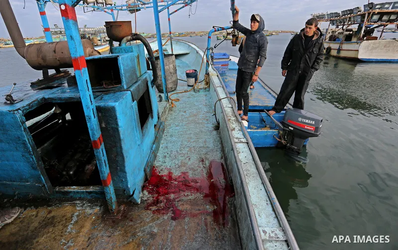 Palestinians inspect a boat at the port in Gaza City on February 26, 2018 in which a fisherman was killed when Israeli forces opened fire on it the previous day. A spokeswoman for the Israeli army said the boat "deviated...