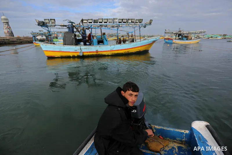 A Palestinian man sits next to a boat at the port in Gaza City on February 26, 2018 in which a fisherman was killed when Israeli forces opened fire on it the previous day. A spokeswoman for the Israeli army said the boat...
