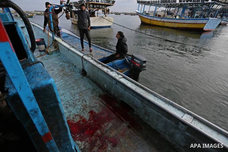 Palestinians inspect a boat at the port in Gaza City on February 26, 2018 in which a fisherman was killed when Israeli forces opened fire on it the previous day. A spokeswoman for the Israeli army said the boat "deviated...