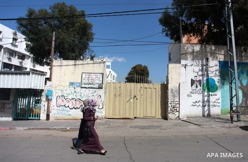 Palestinians walk past closed gates of school during a general strike for government ministries in Gaza City on February 26, 2018. Photo by Mahmoud Ajour