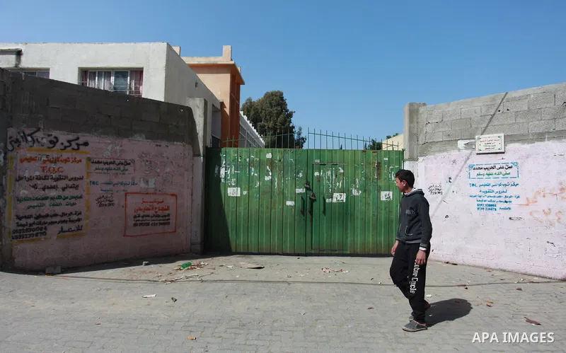 A Palestinian walks past closed gates of school during a general strike for government ministries in Gaza City on February 26, 2018. Photo by Mahmoud Ajour