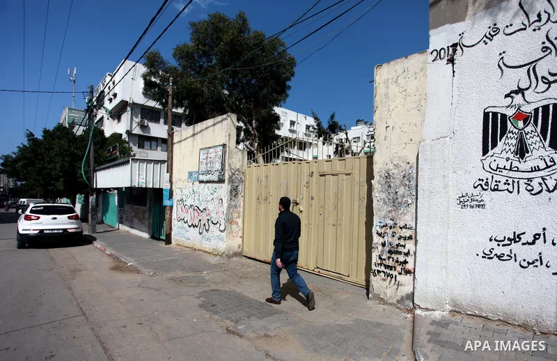 A Palestinian walks past closed gates of school during a general strike for government ministries in Gaza City on February 26, 2018. Photo by Mahmoud Ajour