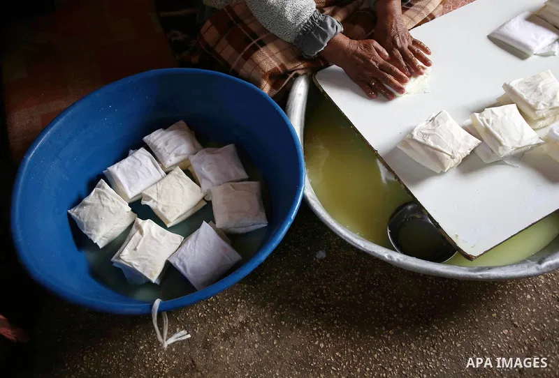 An elderly Palestinian woman Hayat Zeid , 80, makes templates of white cheese inside her home, in Kfairet village near the West Bank city of Jenin, on Febraruy 24, 2018. Hayat has been making cheese from sheep milk since...