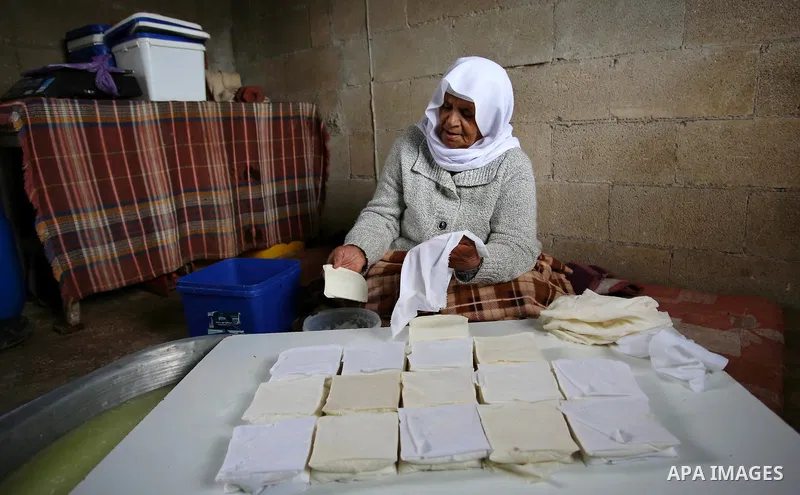 An elderly Palestinian woman Hayat Zeid , 80, makes templates of white cheese inside her home, in Kfairet village near the West Bank city of Jenin, on Febraruy 24, 2018. Hayat has been making cheese from sheep milk since...