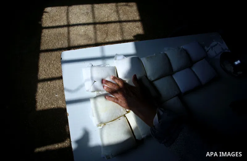 An elderly Palestinian woman Hayat Zeid , 80, makes templates of white cheese inside her home, in Kfairet village near the West Bank city of Jenin, on Febraruy 24, 2018. Hayat has been making cheese from sheep milk since...