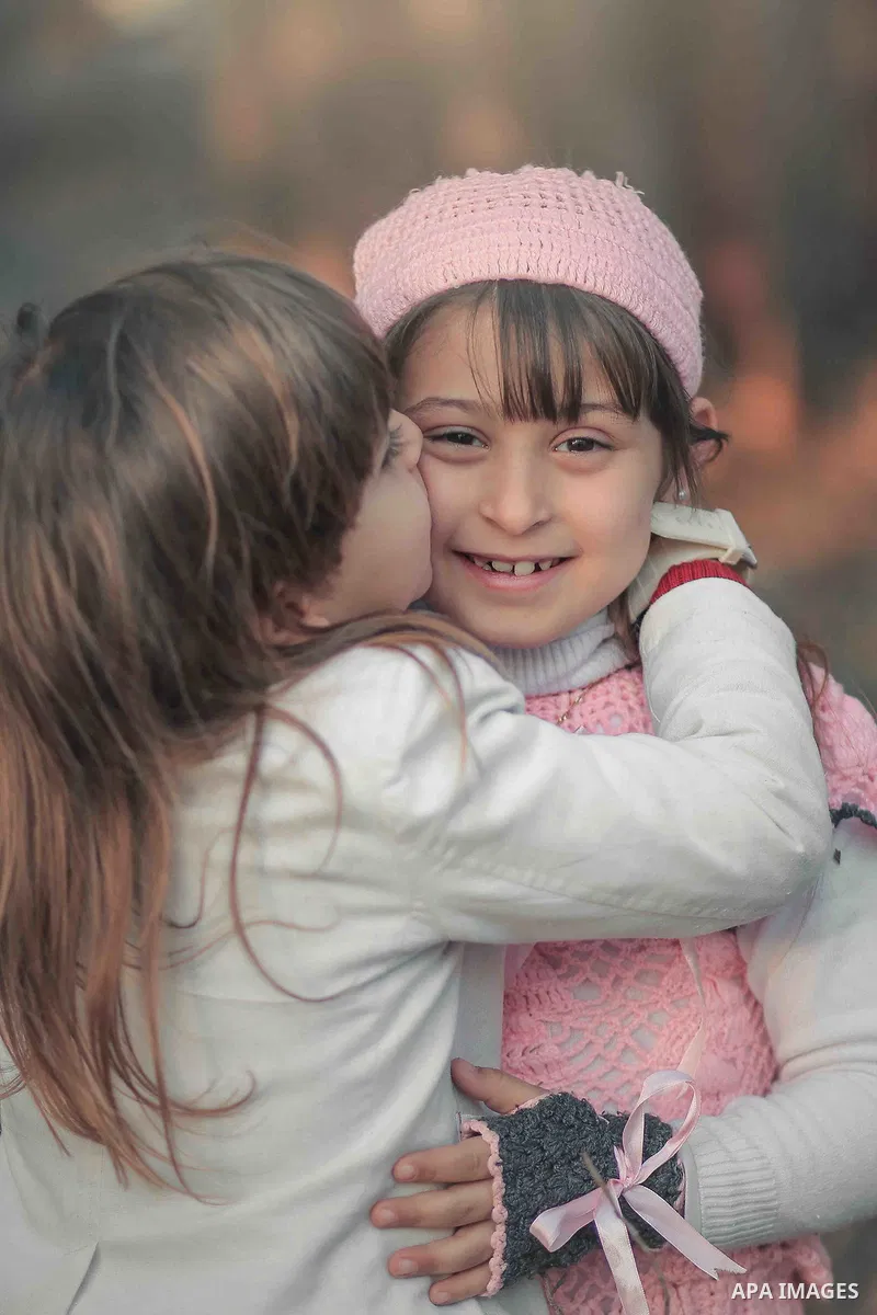 A boy kisses his sister. Photo by Sanad Ltefa