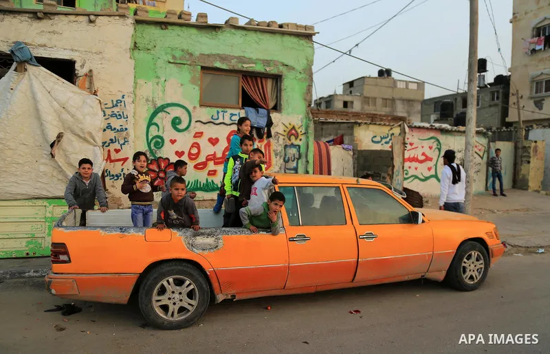 Palestinian children sit on the back of a Mercedes 6-door taxi converted into a pick-up vehicle in the al-Shati refugee camp in Gaza City on February 26, 2018. Photo by Dawoud Abo Alkas