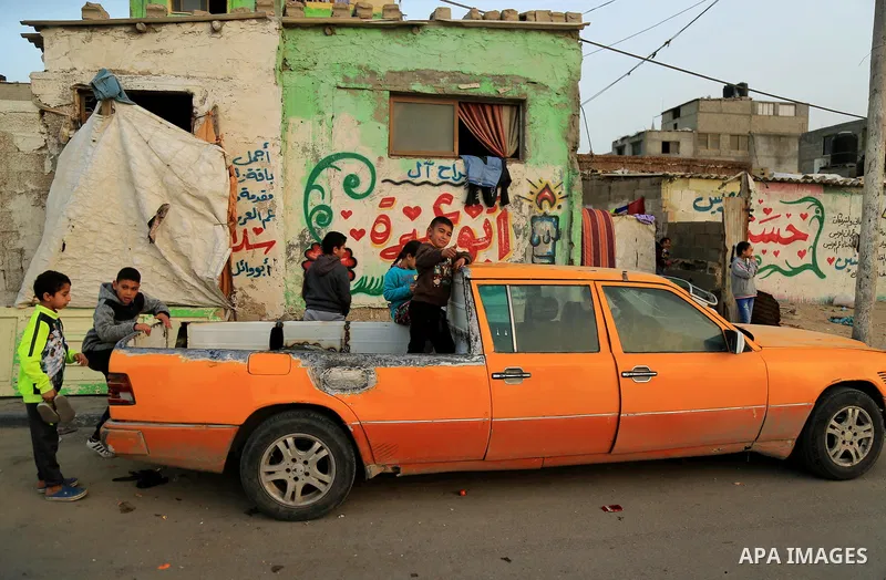 Palestinian children sit on the back of a Mercedes 6-door taxi converted into a pick-up vehicle in the al-Shati refugee camp in Gaza City on February 26, 2018. Photo by Dawoud Abo Alkas