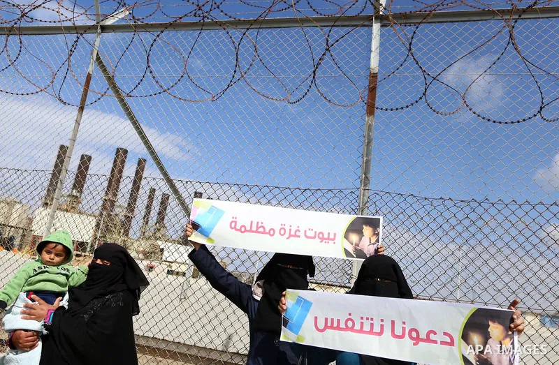 Palestinian women hold banners during a protest calling for an end to the power crisis, outside the power plant in the central Gaza Strip on February 27, 2018. Photo by Yasser Qudih