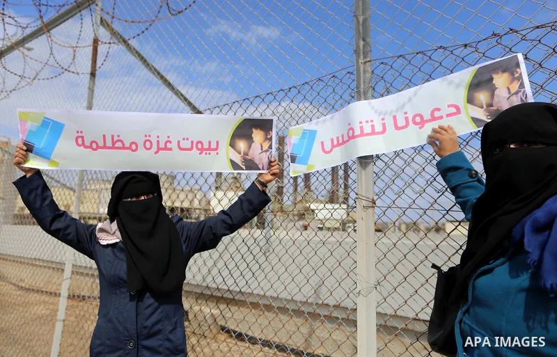 Palestinian women hold banners during a protest calling for an end to the power crisis, outside the power plant in the central Gaza Strip on February 27, 2018. Photo by Yasser Qudih