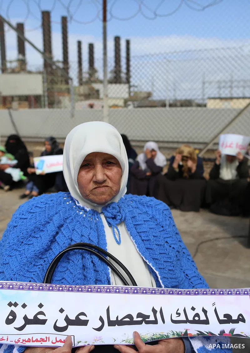 Palestinian women hold banners during a protest calling for an end to the power crisis, outside the power plant in the central Gaza Strip on February 27, 2018. Photo by Yasser Qudih
