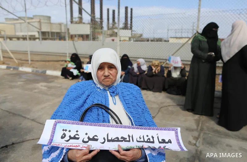 Palestinian women hold banners during a protest calling for an end to the power crisis, outside the power plant in the central Gaza Strip on February 27, 2018. Photo by Yasser Qudih
