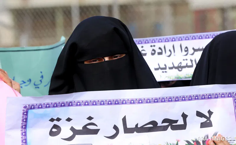 Palestinian women hold banners during a protest calling for an end to the power crisis, outside the power plant in the central Gaza Strip on February 27, 2018. Photo by Yasser Qudih