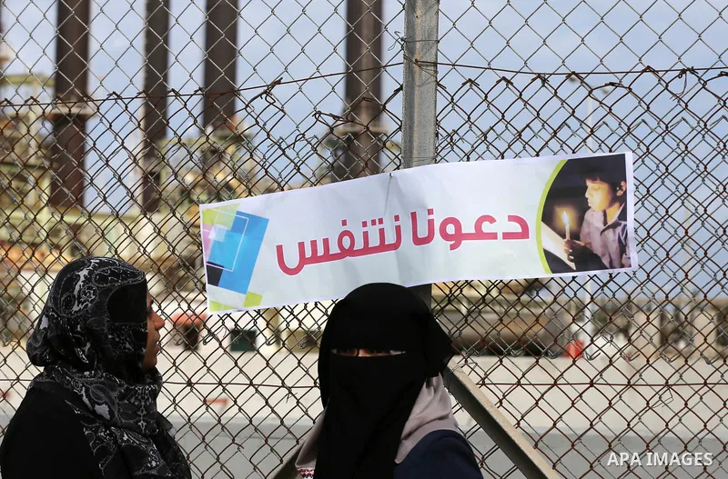 Palestinian women hold banners during a protest calling for an end to the power crisis, outside the power plant in the central Gaza Strip on February 27, 2018. Photo by Yasser Qudih