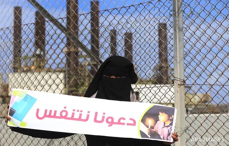 Palestinian women hold banners during a protest calling for an end to the power crisis, outside the power plant in the central Gaza Strip on February 27, 2018. Photo by Yasser Qudih