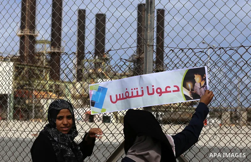 Palestinian women hold banners during a protest calling for an end to the power crisis, outside the power plant in the central Gaza Strip on February 27, 2018. Photo by Yasser Qudih