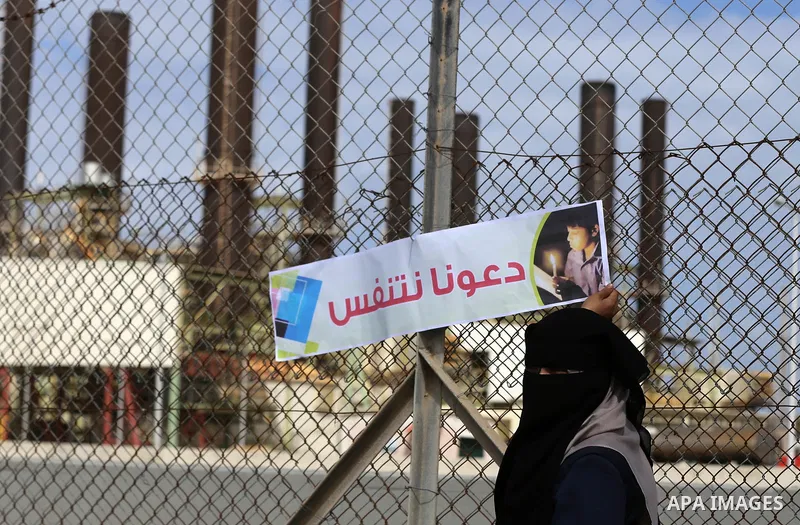Palestinian women hold banners during a protest calling for an end to the power crisis, outside the power plant in the central Gaza Strip on February 27, 2018. Photo by Yasser Qudih
