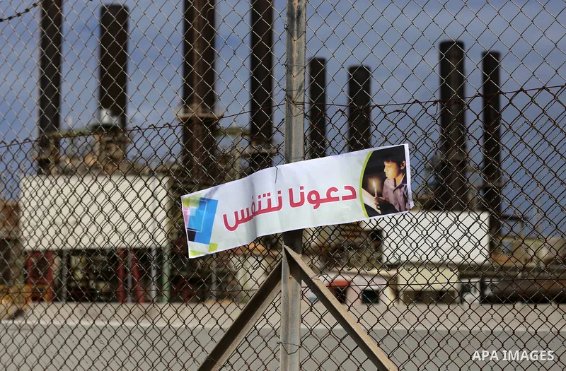 Palestinian women hold banners during a protest calling for an end to the power crisis, outside the power plant in the central Gaza Strip on February 27, 2018. Photo by Yasser Qudih