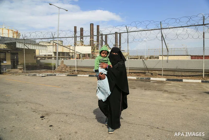 A Palestinian woman holds her son during a protest calling for an end to the power crisis, outside the power plant in the central Gaza Strip on February 27, 2018. Photo by Dawoud Abo Alkas