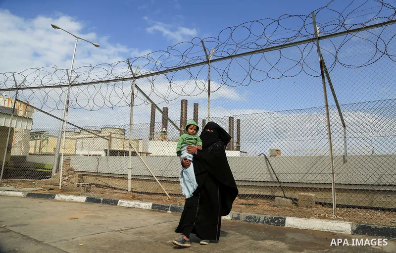 A Palestinian woman holds her son during a protest calling for an end to the power crisis, outside the power plant in the central Gaza Strip on February 27, 2018. Photo by Dawoud Abo Alkas