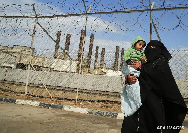 A Palestinian woman holds her son during a protest calling for an end to the power crisis, outside the power plant in the central Gaza Strip on February 27, 2018. Photo by Dawoud Abo Alkas