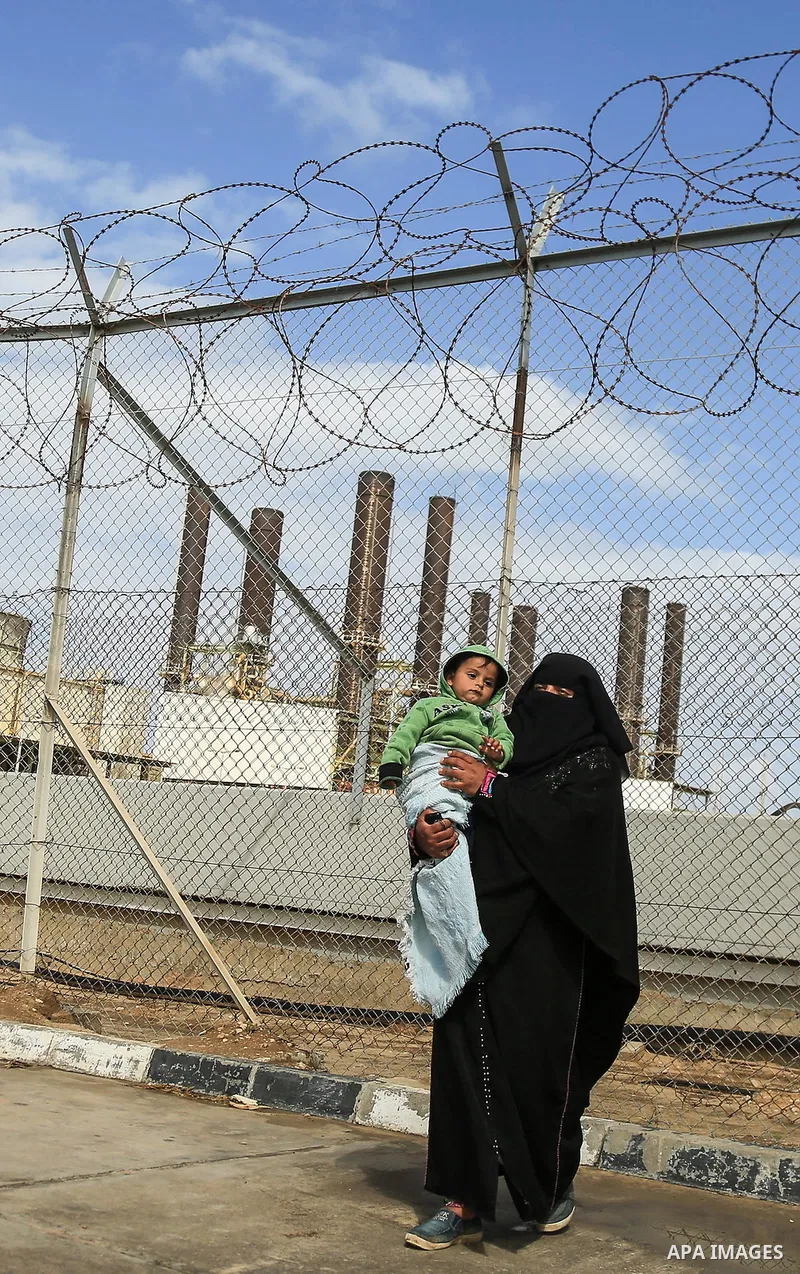 A Palestinian woman holds her son during a protest calling for an end to the power crisis, outside the power plant in the central Gaza Strip on February 27, 2018. Photo by Dawoud Abo Alkas